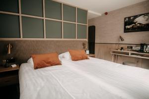 a bedroom with a large white bed with two orange pillows at Witte Berken Natuurhotel in Epe