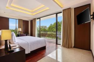 a bedroom with a bed and a balcony with a television at Bali Nusa Dua Hotel in Nusa Dua