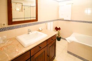 ein Badezimmer mit einem Waschbecken, einem Spiegel und einer Badewanne in der Unterkunft Quinta de Malta in Durrães