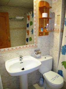 a bathroom with a sink and a toilet and a mirror at Hostal Sol Bahía San José in San José