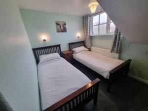 two beds in a small room with a window at The Harp Inn in Glasbury