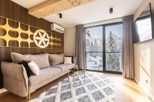 a living room with a couch and a large window at Tatry Residence SPA in Kościelisko