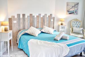 um quarto com uma cama grande com lençóis e almofadas azuis e brancas em Bed & Breakfast My Home - Alassio em Alassio