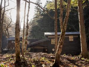 eine Hütte im Wald mit Bäumen im Vordergrund in der Unterkunft Sumiya Rakusuitei - Vacation STAY 17241v in Takayama