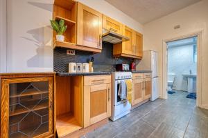 a kitchen with wooden cabinets and white appliances at Stylish & Cosy in Coventry Garden Parking in Coventry