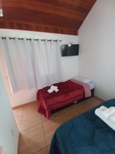 Habitación con 2 camas y manta roja. en Suites Estrela en São Pedro da Serra