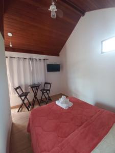 um quarto com uma cama vermelha, uma mesa e cadeiras em Suites Estrela em São Pedro da Serra