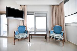 a living room with two chairs and a table and a tv at Orchid Hotel by HolyGuest in Tel Aviv