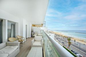 a balcony with a view of the beach and a lighthouse at Orchid Hotel by HolyGuest in Tel Aviv