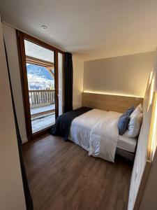 1 dormitorio con cama y ventana grande en Magnifique vue - Pistes 1 min - Parking possible, en Saint-Jean-dʼAulps