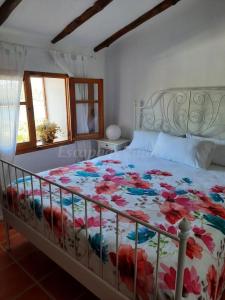 1 dormitorio con 1 cama con colcha de flores en Caserio Los Chacones, en Moratalla