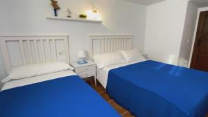 2 camas en una habitación de color azul y blanco en Caserio Los Chacones, en Moratalla