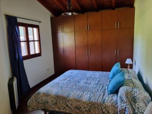 1 dormitorio con 1 cama con almohadas azules y armarios de madera en La Soleada en San Lorenzo