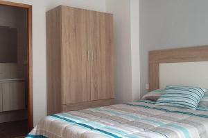een slaapkamer met een bed en een houten kast bij Coqueto alojamiento cercano a las termas in Ourense