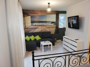 sala de estar con sofá negro y almohadas verdes en Apartament Baltic Sea, en Gdansk