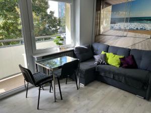 a living room with a blue couch and a glass table at Apartament Baltic Sea in Gdańsk