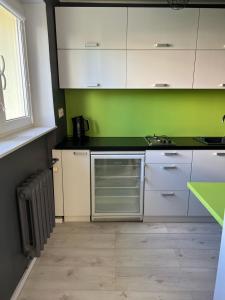 una cocina con armarios blancos y una pared verde en Apartament Baltic Sea, en Gdansk 2 fotos más