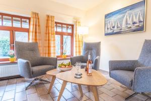 ein Wohnzimmer mit Stühlen und einem Tisch mit einer Flasche Wein in der Unterkunft Ferienhaussiedlung Strandperlen Sanddornhof 4b (Typ IX) in Wustrow