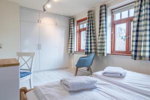 um quarto com 2 camas, uma cadeira e janelas em Ferienhaussiedlung Strandperlen Sanddornhof 4b (Typ IX) em Wustrow