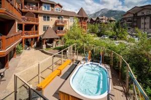 uma piscina exterior com uma banheira de hidromassagem num edifício em Mountain View 1 BR Condo With Gym & Hot-Tubs em Canmore