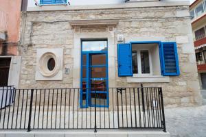 a building with blue doors and a fence at Vacanze a Casa Pozzallo in Pozzallo