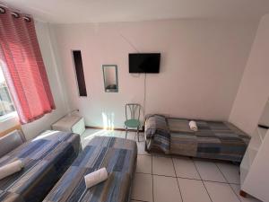 a room with two beds and a flat screen tv at Residencial Louise in Balneário Camboriú