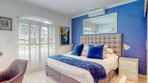 1 dormitorio con paredes azules y 1 cama con almohadas azules en Rose Cottage in Caribbean Estate, en Port Edward