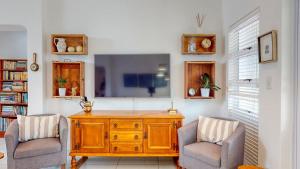 a living room with a tv and two chairs at Rose Cottage in Caribbean Estate in Port Edward