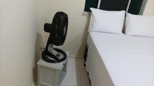 een slaapkamer met een bed en een zwarte ventilator op een nachtkastje bij Apartamento aconchegante próximo à UFS in São Cristóvão