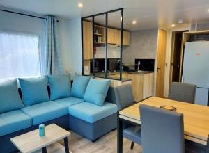 a living room with a blue couch and a table at Mobil home dans un camping **** la réserve / siblu in Gastes