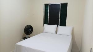 a white bed with two white pillows and a window at Apartamento aconchegante próximo à UFS in São Cristóvão