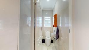 a white bathroom with a toilet and a sink at Rose Cottage in Caribbean Estate in Port Edward