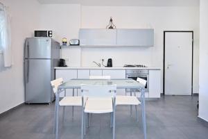 een keuken met een tafel en stoelen en een koelkast bij Winds of Change by HolyGuest in Tel Aviv