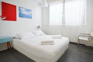 een witte slaapkamer met een wit bed en een raam bij Winds of Change by HolyGuest in Tel Aviv