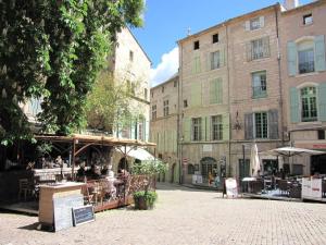 eine Straße mit Tischen, Stühlen und Gebäuden in der Unterkunft Au QUATRE, 2em étage centre historique in Pézenas