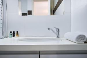 een witte badkamer met een wastafel en een spiegel bij Winds of Change by HolyGuest in Tel Aviv