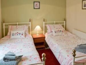 two twin beds in a bedroom with a lamp at Hay Cottage in Saint Stephen