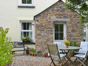 a table and chairs in front of a stone house at Hay Cottage in Saint Stephen