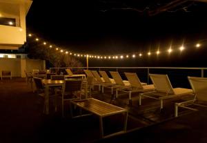 a group of chairs and tables on a deck at night at Bella Surf Inn in Isabela