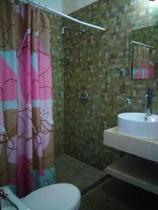 a bathroom with a shower curtain and a toilet and a sink at LOS ARCOS in Agua Buena
