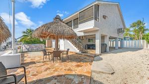 a house with a patio with chairs and a table at Tavernier Keys Home w/70’ Dock & 20k Boat Lift on Bayside! 3/2.5 Plus Game Room in Tavernier