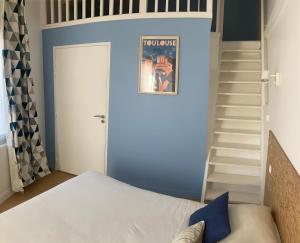 ein Schlafzimmer mit einer blauen Wand und einer Treppe in der Unterkunft Résidence Thibaud in Toulouse