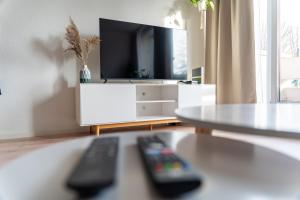 a living room with two remote controls in front of a tv at Green-Art-Living: NEW BOHO Style Central für 2 in Kempten