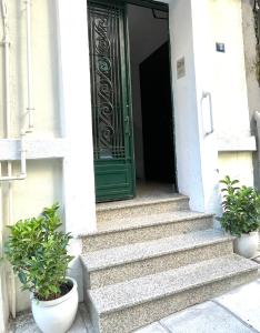 a green door on a white building with two potted plants at Ministerium underground studio in Thessaloniki