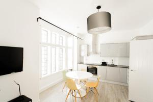 uma cozinha branca com uma mesa e cadeiras brancas em The Apartments Kensington High Street em Londres