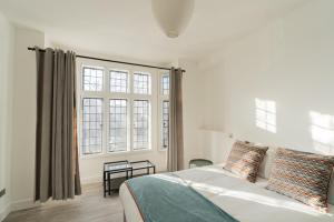 um quarto com uma cama e uma grande janela em The Apartments Kensington High Street em Londres