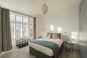 a bedroom with a large bed with two windows at The Apartments Kensington High Street in London