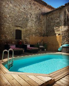 una gran piscina en un patio con una pared de piedra en Suite partner, en Peyriac-Minervois