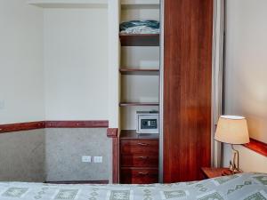 1 dormitorio con 1 cama y un armario con microondas en Aunaisin-Viejo lobo en Ushuaia
