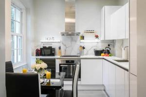 a kitchen with white cabinets and a table with drinks on it at Modern 3 and 2 bedroom flat in central london with full AC in London